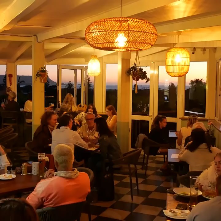 Guests dining by the big windows as the sun goes down